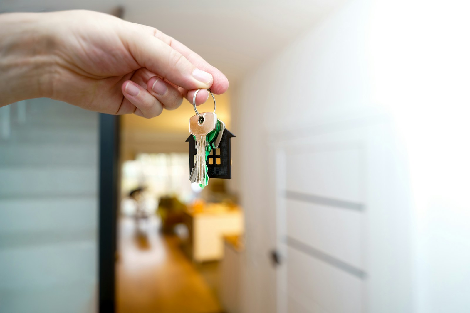 Hand holding a door key inside a home
